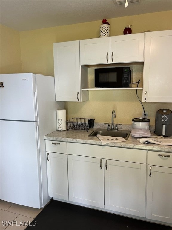 kitchen with white cabinetry, sink, and white refrigerator