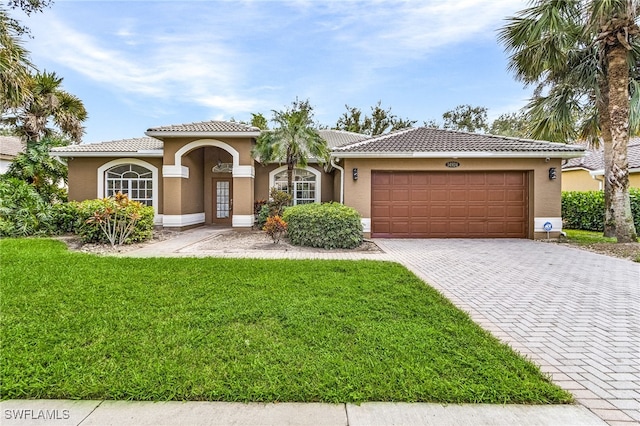 mediterranean / spanish house featuring a garage and a front lawn