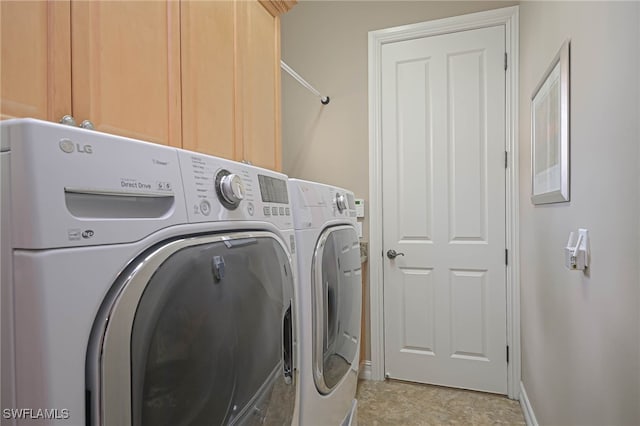 clothes washing area featuring washer and dryer and cabinets