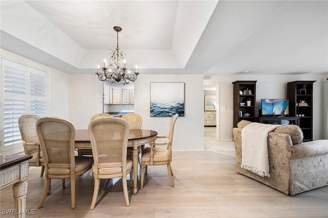 dining room with a chandelier, light hardwood / wood-style floors, and a tray ceiling