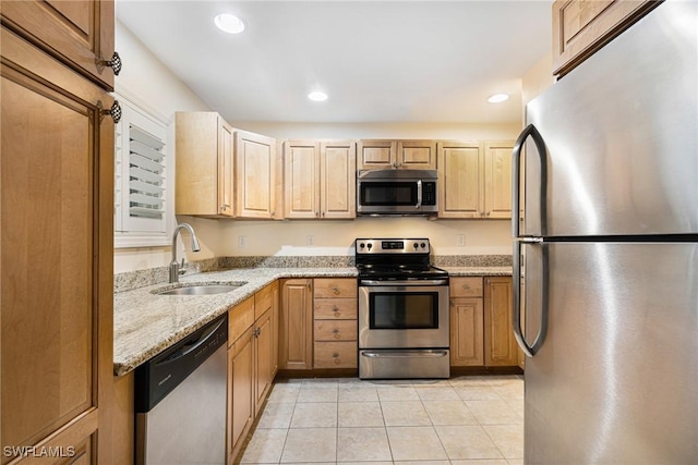 kitchen featuring sink, light tile patterned floors, appliances with stainless steel finishes, light stone counters, and light brown cabinetry