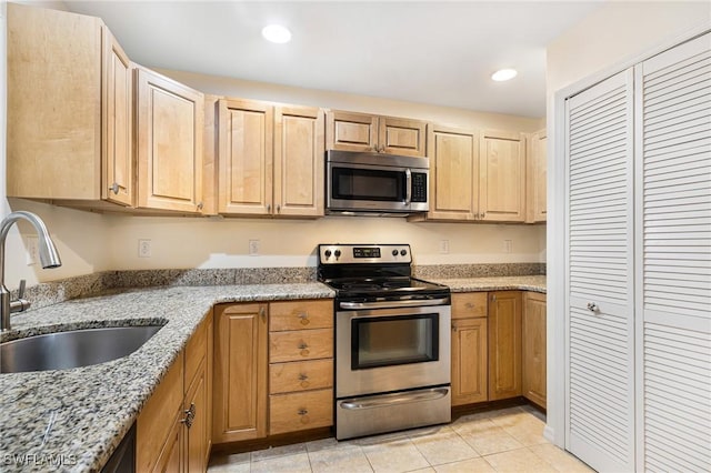 kitchen featuring light brown cabinetry, sink, light tile patterned floors, light stone counters, and stainless steel appliances