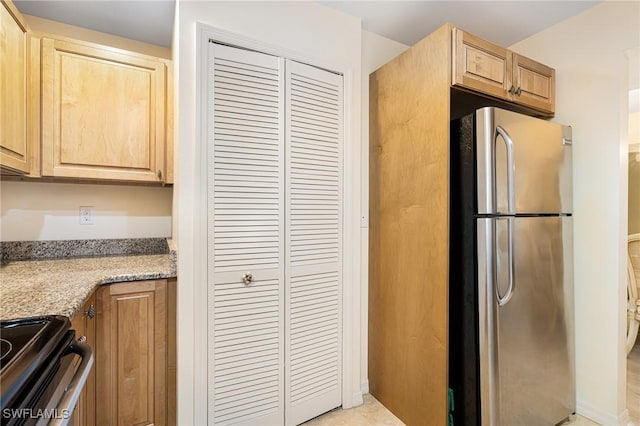 kitchen featuring electric range, stainless steel fridge, light stone countertops, and light brown cabinets