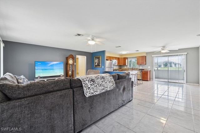 living room with ceiling fan, light tile patterned flooring, and sink