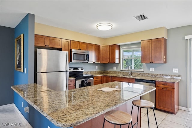 kitchen with a breakfast bar, stainless steel appliances, light stone countertops, and sink