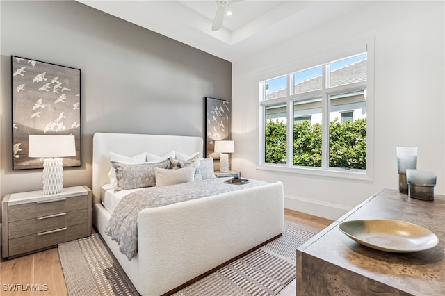 bedroom with ceiling fan, light hardwood / wood-style floors, and multiple windows