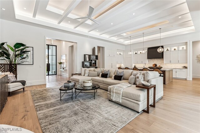 living room featuring ceiling fan, light hardwood / wood-style floors, and beam ceiling