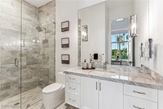 bathroom featuring vanity, a shower with shower door, and toilet