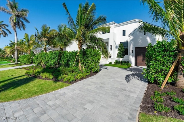 view of front of home with a front lawn, decorative driveway, and stucco siding