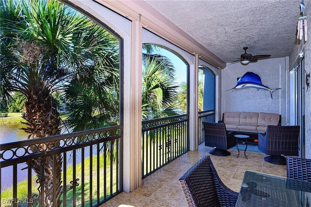 balcony with ceiling fan and a water view