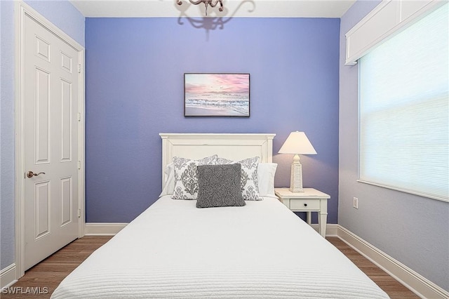 bedroom with multiple windows, hardwood / wood-style floors, and a notable chandelier