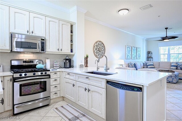 kitchen with stainless steel appliances, decorative backsplash, kitchen peninsula, and sink