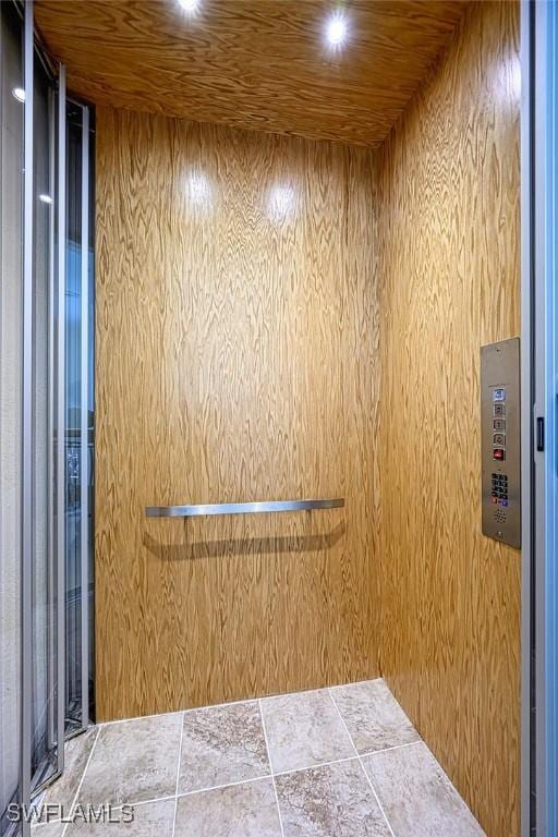 details with wooden ceiling, elevator, and wood walls