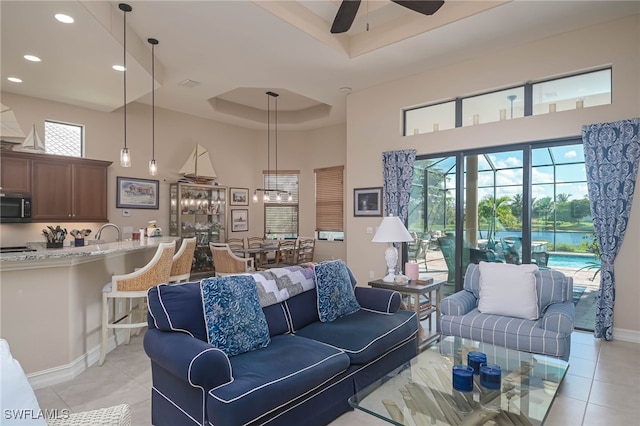 tiled living room featuring a raised ceiling, a towering ceiling, ceiling fan, and plenty of natural light