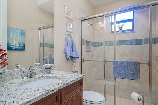 bathroom with walk in shower, vanity, and toilet