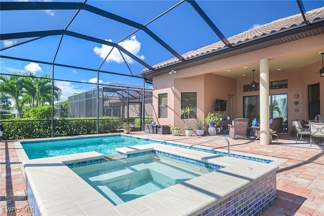 view of pool with glass enclosure, an in ground hot tub, ceiling fan, and a patio