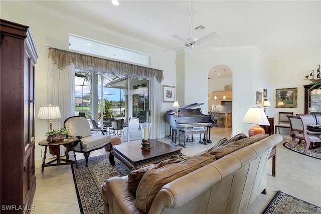 tiled living room with ornamental molding, a towering ceiling, and ceiling fan