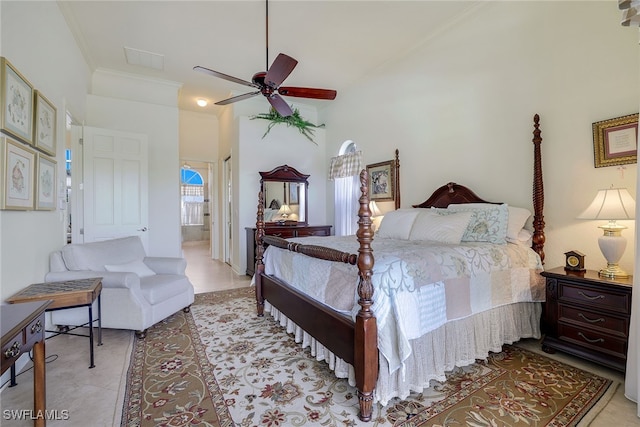 tiled bedroom featuring ceiling fan, ensuite bath, a towering ceiling, and crown molding