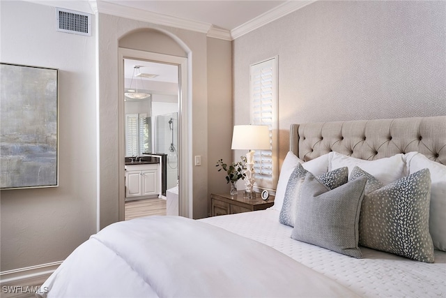 bedroom with light hardwood / wood-style floors, connected bathroom, and ornamental molding