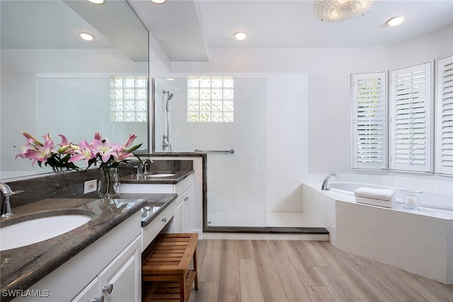 bathroom with wood-type flooring, independent shower and bath, and vanity