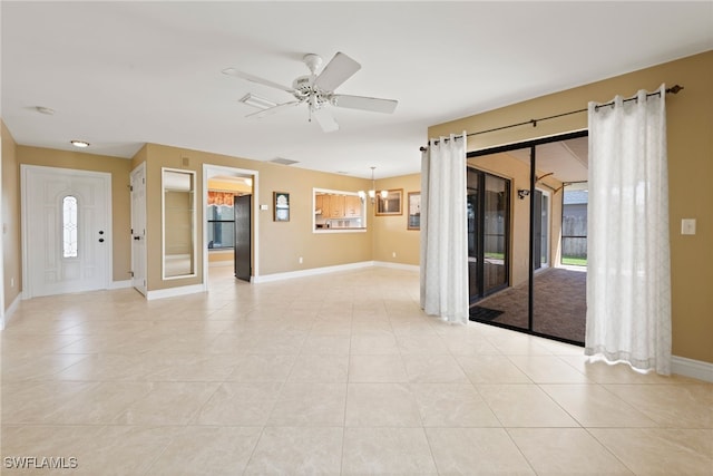 tiled empty room featuring ceiling fan with notable chandelier