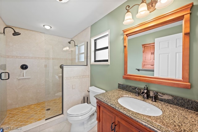 bathroom featuring tile patterned floors, vanity, toilet, and a shower with door