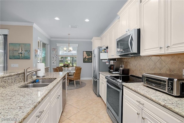 kitchen with appliances with stainless steel finishes, backsplash, sink, white cabinets, and hanging light fixtures