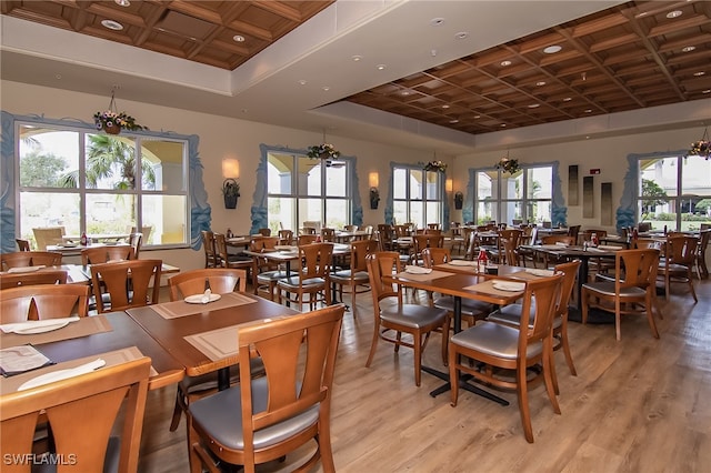 dining area featuring light wood-type flooring, a wealth of natural light, and coffered ceiling