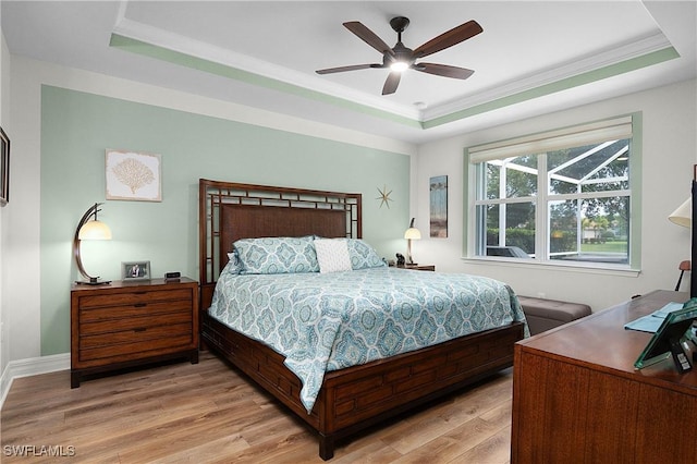 bedroom featuring a raised ceiling, ceiling fan, crown molding, and light wood-type flooring