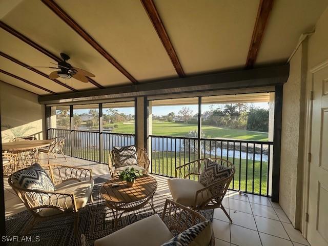 sunroom / solarium with ceiling fan, a water view, and a wealth of natural light