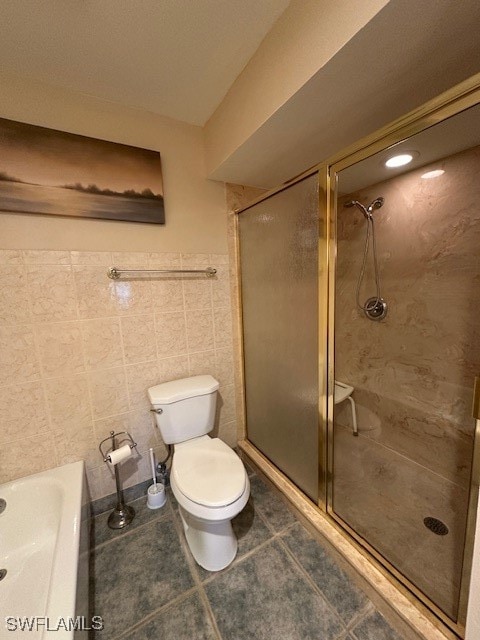 bathroom with tile patterned flooring, toilet, tile walls, and a shower with shower door