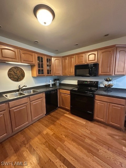 kitchen with black appliances, sink, and light hardwood / wood-style flooring