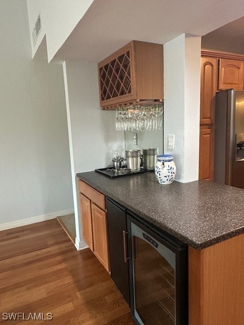 bar featuring stainless steel fridge with ice dispenser, dark wood-type flooring, and beverage cooler