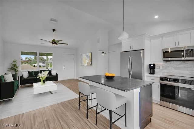 kitchen with a kitchen bar, white cabinetry, a kitchen island, backsplash, and stainless steel appliances