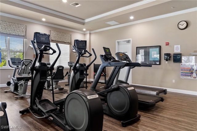 exercise room featuring ornamental molding, dark hardwood / wood-style floors, and a raised ceiling