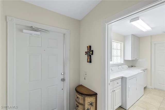 clothes washing area with cabinets, light tile patterned floors, and washing machine and clothes dryer