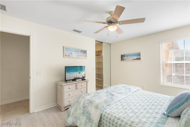 bedroom with a spacious closet, ceiling fan, light wood-type flooring, and a closet