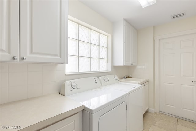 clothes washing area featuring washer and clothes dryer, light tile patterned floors, cabinets, and sink