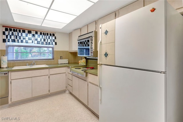 kitchen with backsplash, dishwasher, white fridge, sink, and stovetop