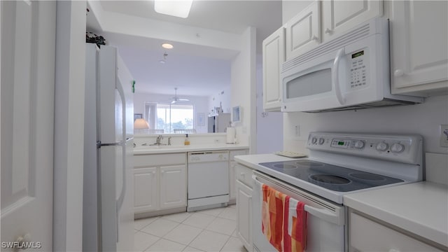 kitchen with white appliances, sink, light tile patterned floors, and white cabinets