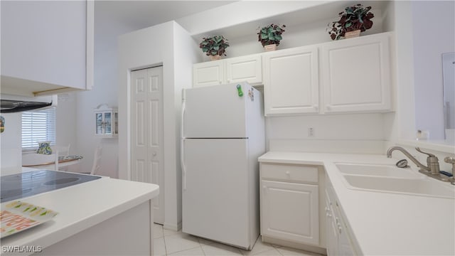 kitchen with white cabinets, white refrigerator, light tile patterned flooring, and sink