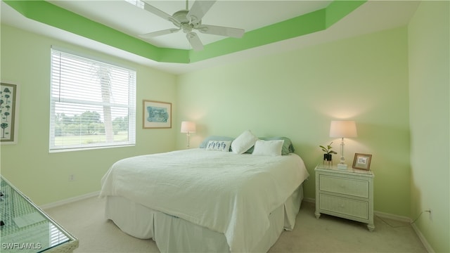 carpeted bedroom featuring ceiling fan and a tray ceiling