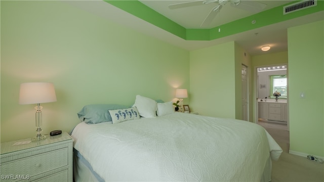 bedroom with light carpet, ensuite bathroom, and ceiling fan