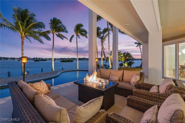 patio terrace at dusk with a water view and an outdoor living space with a fire pit