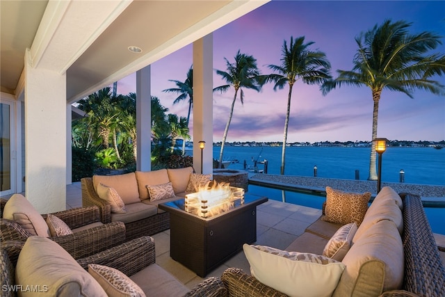 patio terrace at dusk with a water view and an outdoor living space