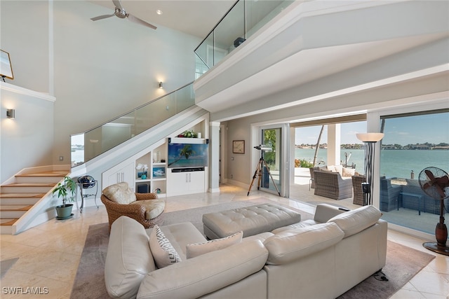 tiled living room with a water view, a towering ceiling, and ceiling fan