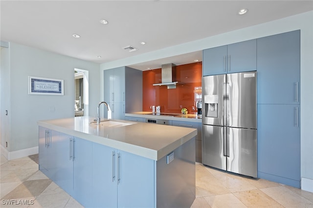 kitchen featuring stainless steel fridge, a center island with sink, sink, and wall chimney exhaust hood