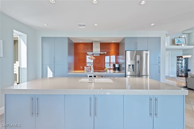 kitchen with an island with sink, stainless steel refrigerator with ice dispenser, sink, and ventilation hood