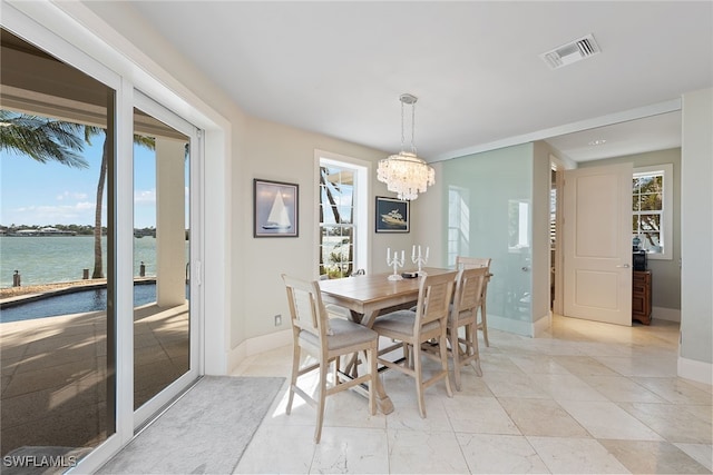 dining space with a water view and a chandelier