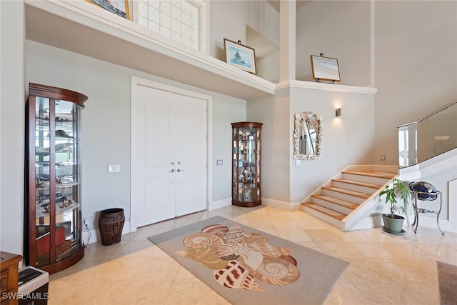 entryway with a towering ceiling and light tile patterned flooring